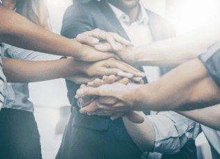 Diverse group of medical professionals joining hands in unity and teamwork