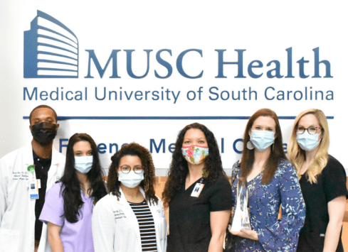 MUSC Health medical staff wearing masks pose in front of hospital sign