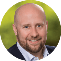 Smiling bald man with beard wearing blue shirt and suit jacket