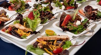 Healthy salad entrees with fresh greens, vegetables, fruits, and lean proteins artfully plated