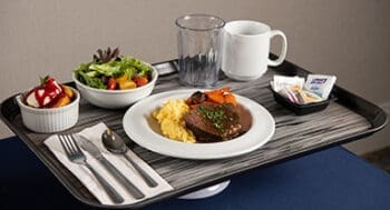 Healthy hospital meal on tray with salad, entree, sides, coffee, water and packaged snacks