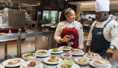 Chef and server discuss food options at modern restaurant kitchen counter