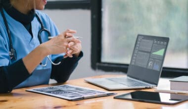 Female doctor reviewing medical data on laptop and digital tablet at office desk