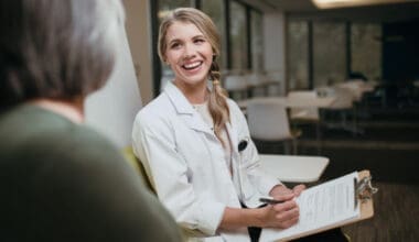 Smiling healthcare worker discussing medical record with patient in hospital cafeteria setting