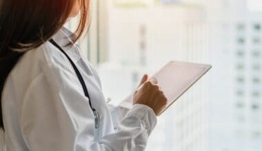 Female doctor reading medical chart in hospital hallway