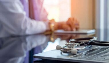 Doctor using laptop with stethoscope, focusing on providing quality healthcare