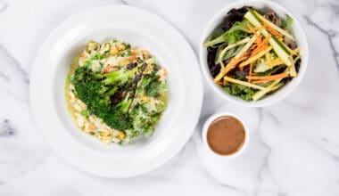 Salmon risotto and colorful salad with carrot ginger dressing on marble table