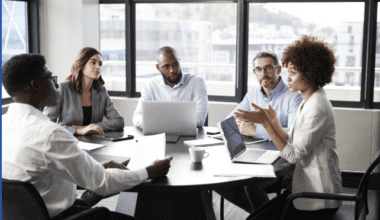 Business team meeting in office boardroom discussing project on laptop