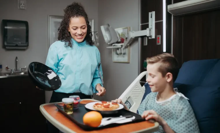 Mother serving breakfast to son in assisted living apartment kitchen