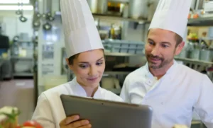 Chefs reviewing menu on tablet in commercial kitchen