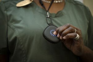 Person holding medical alert device pendant, close-up of hands