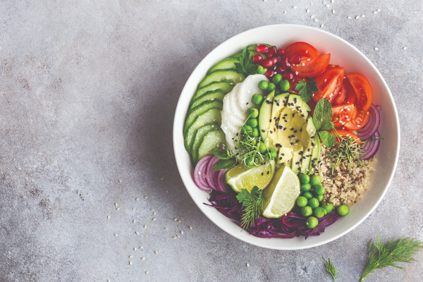 Colorful vegetarian salad bowl with avocado, tomatoes, cucumbers, quinoa and dill on concrete background