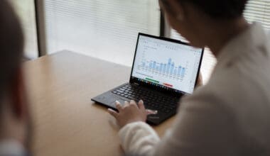 Woman analyzing graph data on laptop, reviewing business metrics and performance