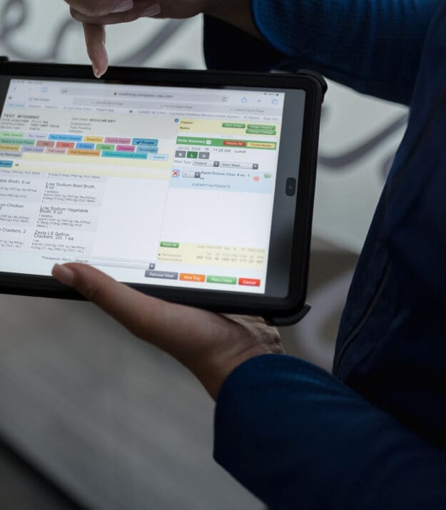 Hands holding tablet displaying color-coded calendar interface for Morrison Healthcare scheduling app