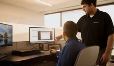 Morrison Healthcare employee assisting child at computer workstations showing scenic images