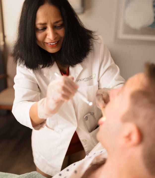 Morrison Healthcare nurse providing attentive patient care with a warm, friendly smile.