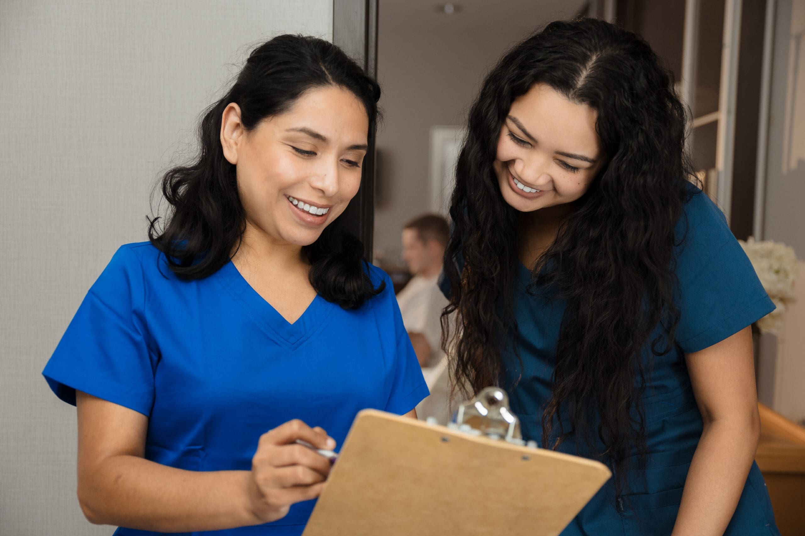 Two smiling healthcare workers reviewing medical paperwork together