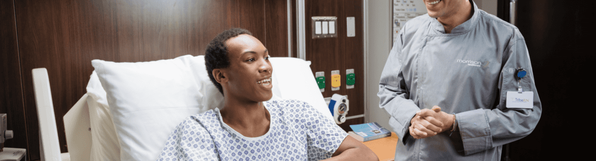 Patient smiling while talking with Morrison Healthcare employee in hospital room