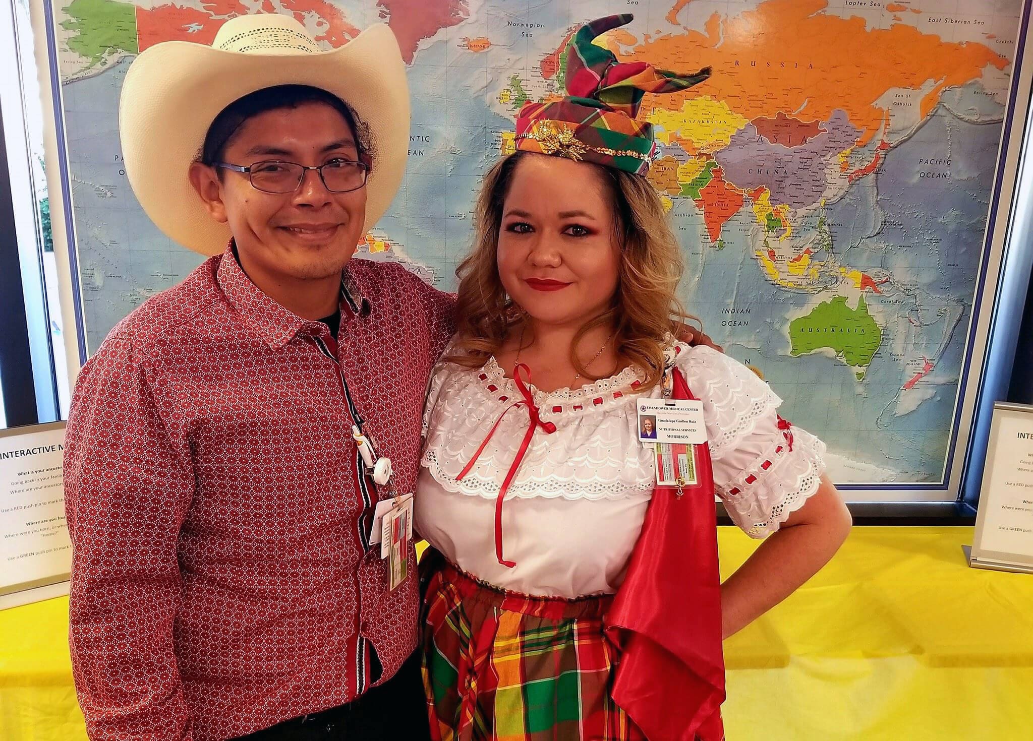 Morrison Healthcare team members in colorful traditional clothing pose in front of a world map