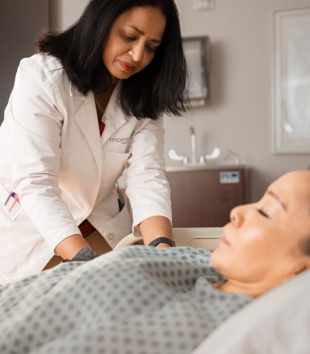 Morrison Healthcare clinician conducts a MyMalnutrition bedside assessment, gently checking on a resting hospital patient.